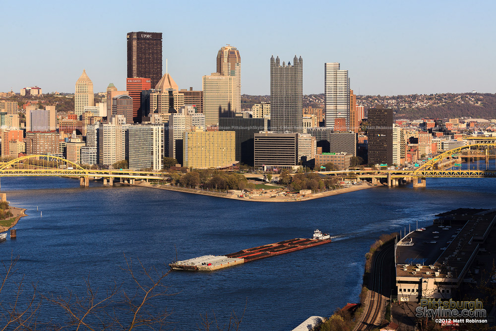Coal barges make their way up the Ohio River with the Pittsburgh Skyline