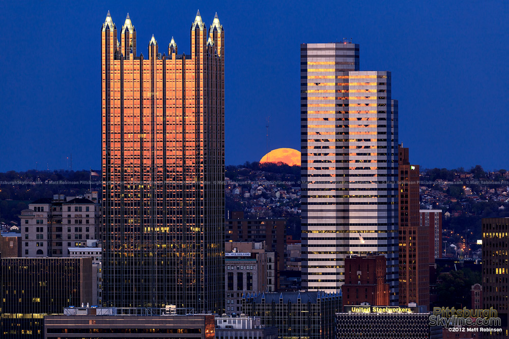 An orange full moon rises between PPG Place and One Oxford Center