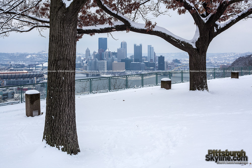 Trees frame Pittsburgh from West End Overlook with snow